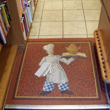 Photograph of the mosaic floor at the entrance depicting a chef